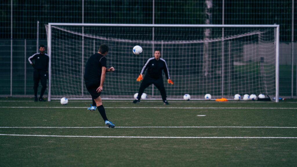 Fußballspieler, der während einer Angriffsübung auf den Torwart schießt.